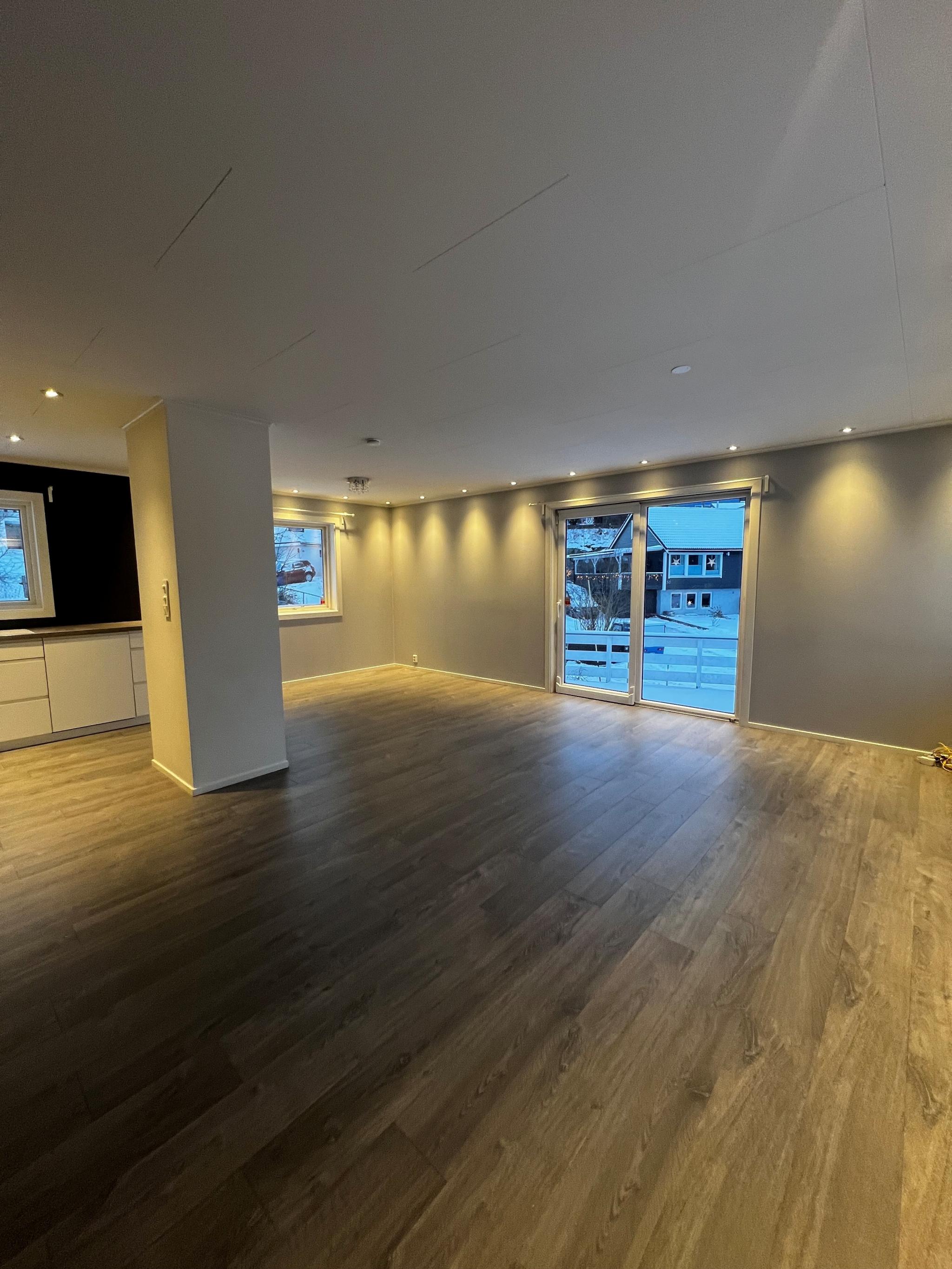 Stue med store vindusflater, åpen kjøkkenløsning